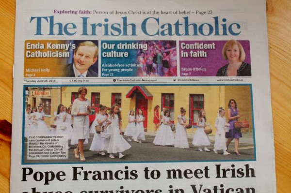 Principal, Joan O'Mahony rings the bell for the HolyCommunion Children of Presentation N.S., Cullen N.S. and Cloghoula N.S. during the Procession.   Teacher Fiona Hurley (nee Mahony) holds the replenishing flower basket.